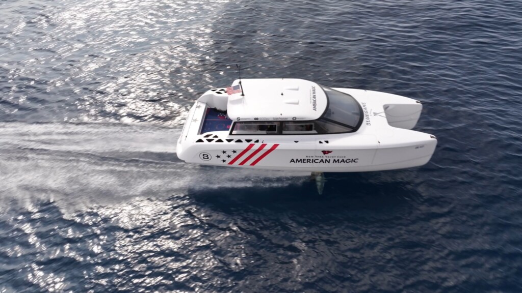 White foiling twin hulled motor yacht flying across the water