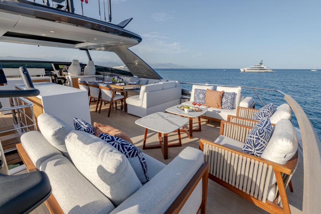 Flybridge of a motor yacht with light coloured sofas and two small marble topped tables